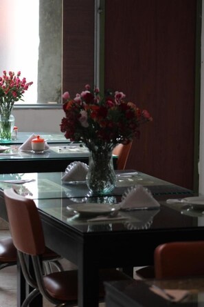 A dining table set with a vase of flowers, a candle, and a shell. - Hotel Real Estación (Bogotá)