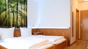 Une chambre à coucher avec un lit en bois, une table de chevet, une lampe fixée au mur et une porte.