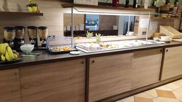 A buffet area with a variety of food items, a fruit display, and a wine selection.