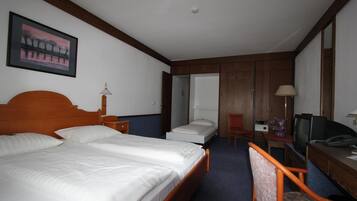 Habitación de hotel con dos camas, un escritorio con computadora, una silla, un televisor y un cuadro en la pared.