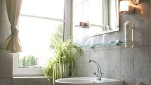 Een badkamer met een wastafel, spiegel en een plant in pot.
