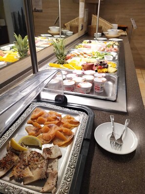 A buffet with various food items, including fruits, vegetables, and seafood. - Hotel Leano (Lübeck)