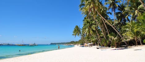 On the beach, white sand, sun-loungers, beach umbrellas