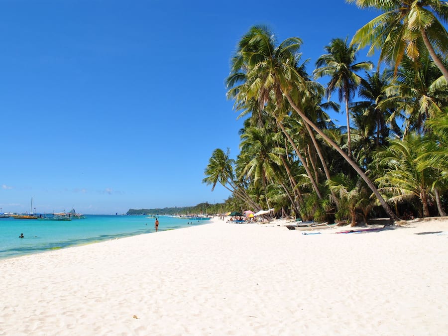 En la playa, arena blanca, sillas reclinables de playa, sombrillas