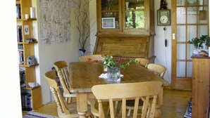 Un comedor con una mesa de madera, sillas, un mapa en la pared y un aparador con puertas de cristal.