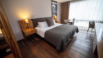 A hotel room with a large bed, a wooden headboard, a nightstand, a desk, and a chair.