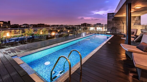 Ein Pool auf dem Dach mit Blick auf die Stadt in der Abenddämmerung.
