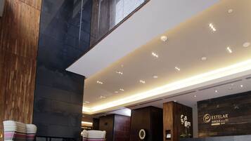 Un vestíbulo amplio con techo alto, iluminación moderna y un mostrador de recepción.