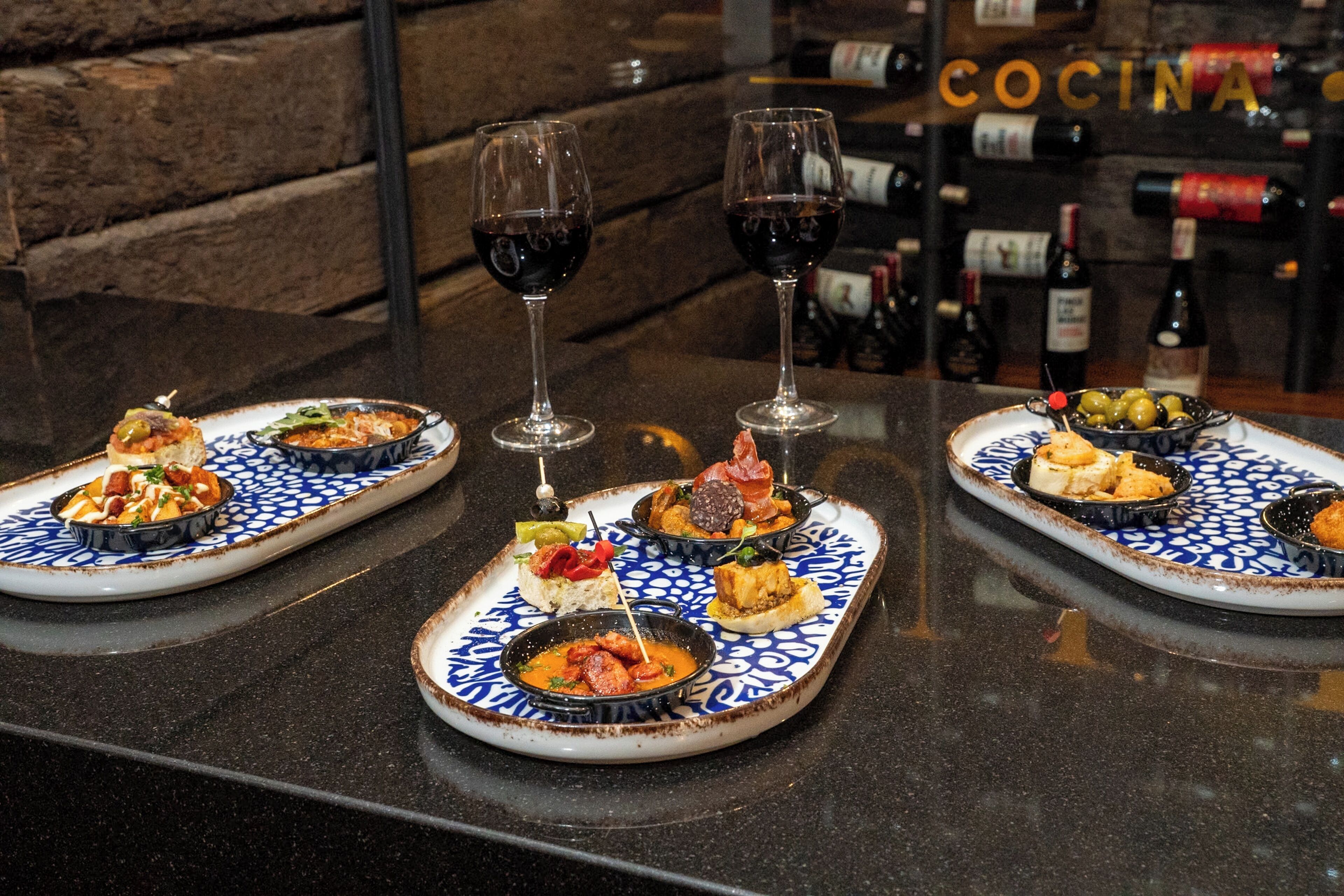 Zona de bar con una estantería de vinos y platos de comida.