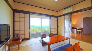Una habitación tradicional japonesa con suelo de tatami, un fusuma que da a un balcón y un televisor a la izquierda.
