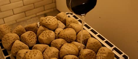 A tray of round bread with a textured surface, being filled with a dark liquid from a ladle.