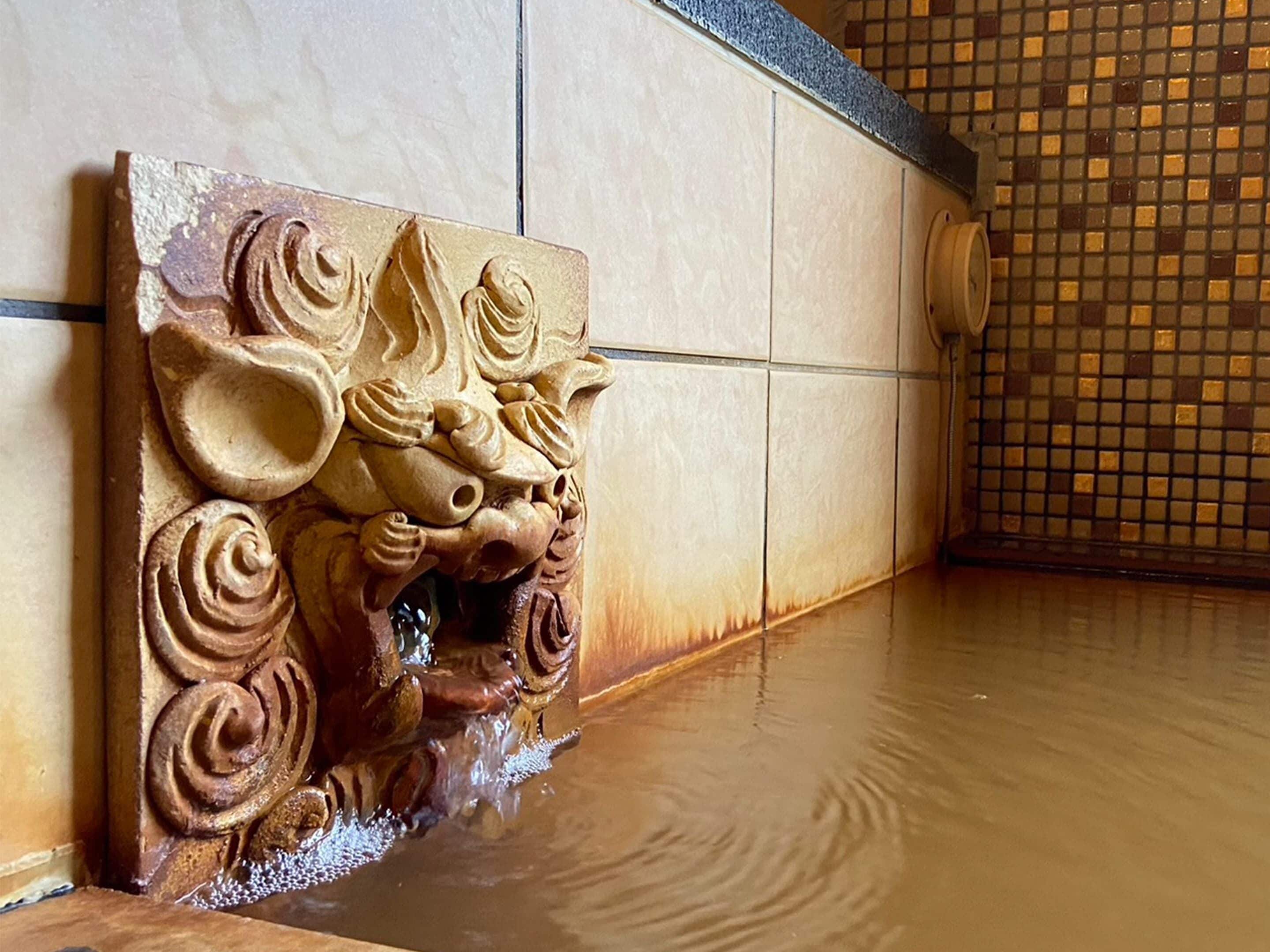 A carved wooden panel with a lion's head design, a tiled wall, and a tiled floor.