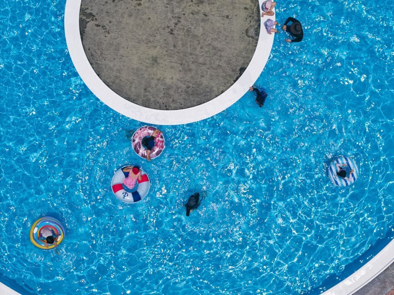 Vista aérea de una piscina con varias personas y flotadores.