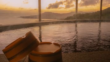Un bain à remous avec vue sur un coucher de soleil se reflétant sur une étendue d’eau et des montagnes.