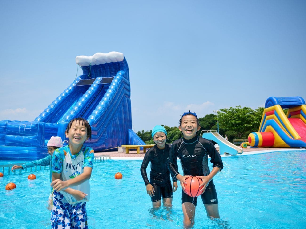 A swimming pool with inflatable water slides and a play area.
