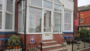A hotel with a red brick facade, white-framed windows, and a sign indicating it is currently vacant. - Sussex Hotel (Blackpool)