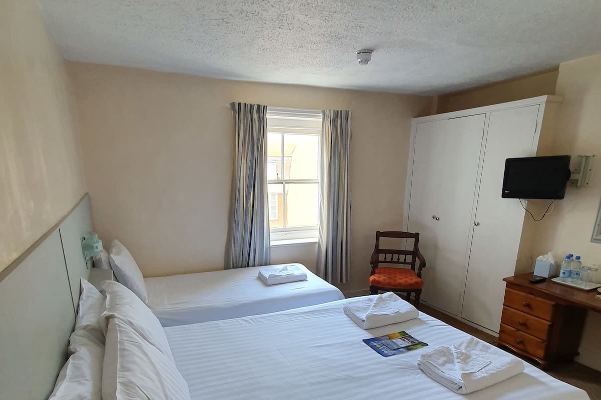 A hotel room with two beds, a desk with a computer, a TV, and a wardrobe.
