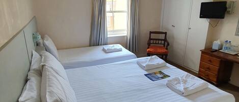 A hotel room with two beds, a desk with a computer, a TV, and a wardrobe.