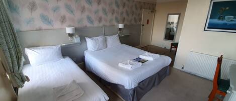 A hotel room with two beds, a radiator, a painting, and a mirror on the wall.