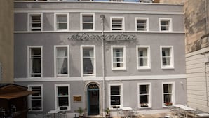 A two-story building with a sign reading "Alexandra" above the entrance. There are outdoor seating areas with tables and chairs. - Alexandra Hotel (Weymouth)