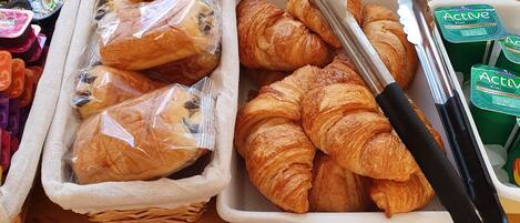 A breakfast buffet with various food items including bread, pastries, and condiments.