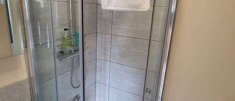 A modern bathroom with a glass-enclosed shower, a white sink, and a small white table.