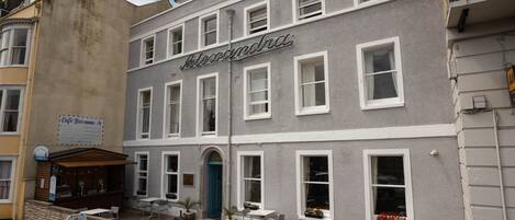 A building with a sign reading "Alexandra" and a café bar sign below it.