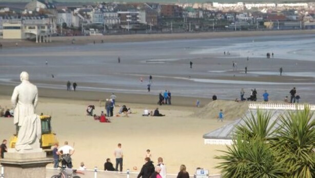 A beach with a statue, people, and buildings in the background. - Alexandra Hotel (Weymouth)