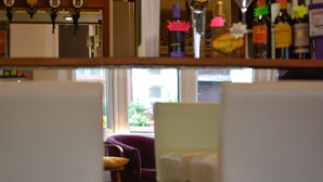 A bar area with a wooden counter and various bottles. There are chairs in the foreground. - The Beaucliffe (Blackpool)