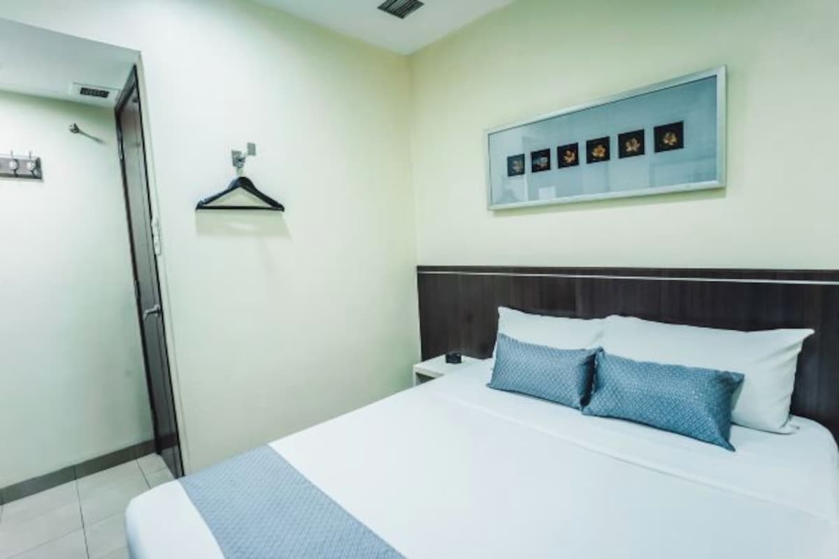 A hotel room with a bed, a nightstand, a wall-mounted picture, and a door.
