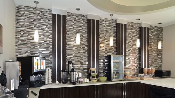 A modern bar area with a counter, coffee machines, and a variety of food items. - Quality Inn & Suites Kenedy - Karnes City (Kenedy)