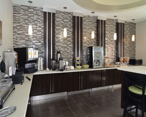 A modern bar area with a counter, coffee machines, and a variety of food items.