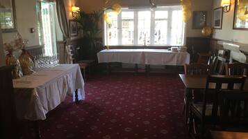 Una habitación con dos mesas dispuestas para comer, una alfombra roja con diseño y vistas amplias a través de grandes ventanales.