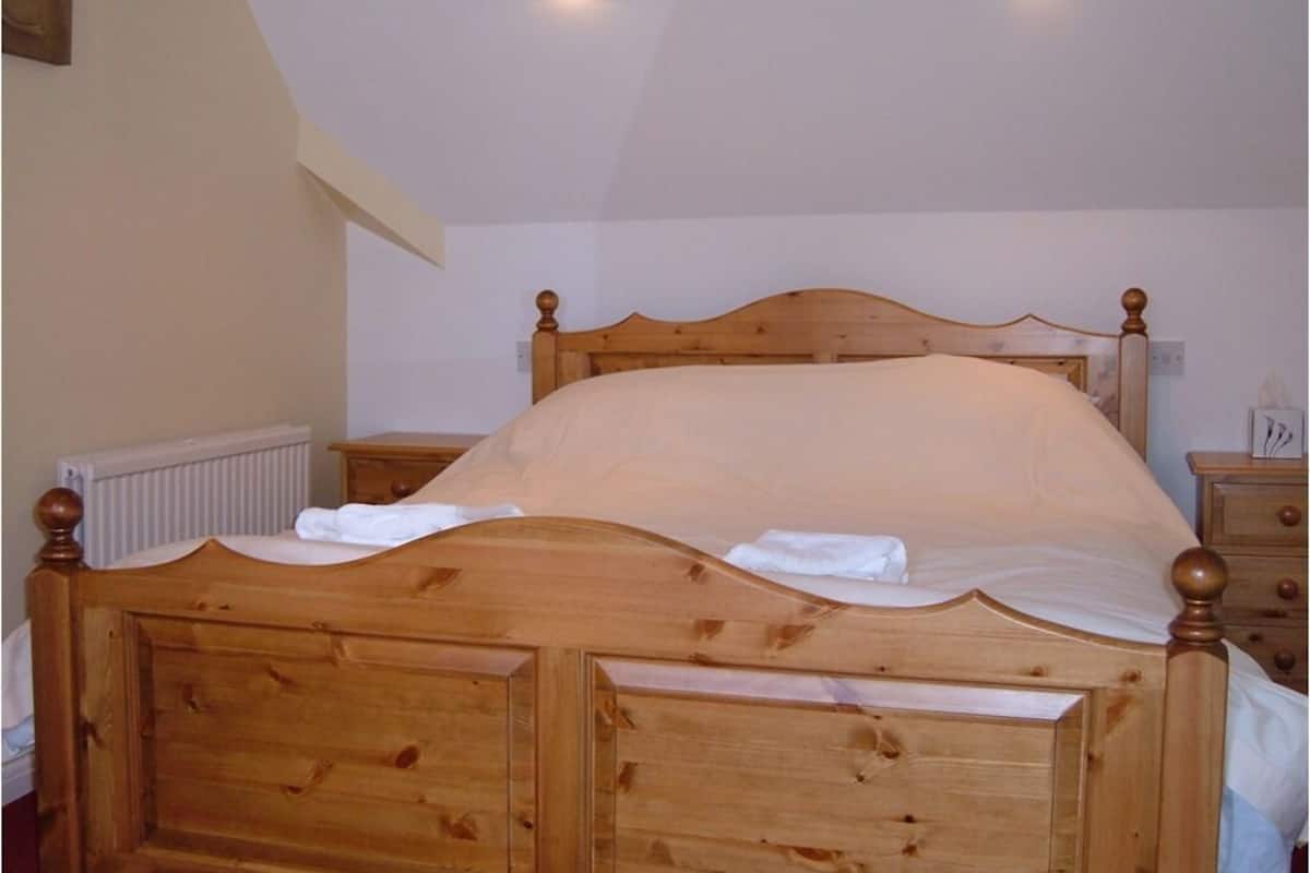 A wooden bed with a headboard, two bedside tables, and a radiator.