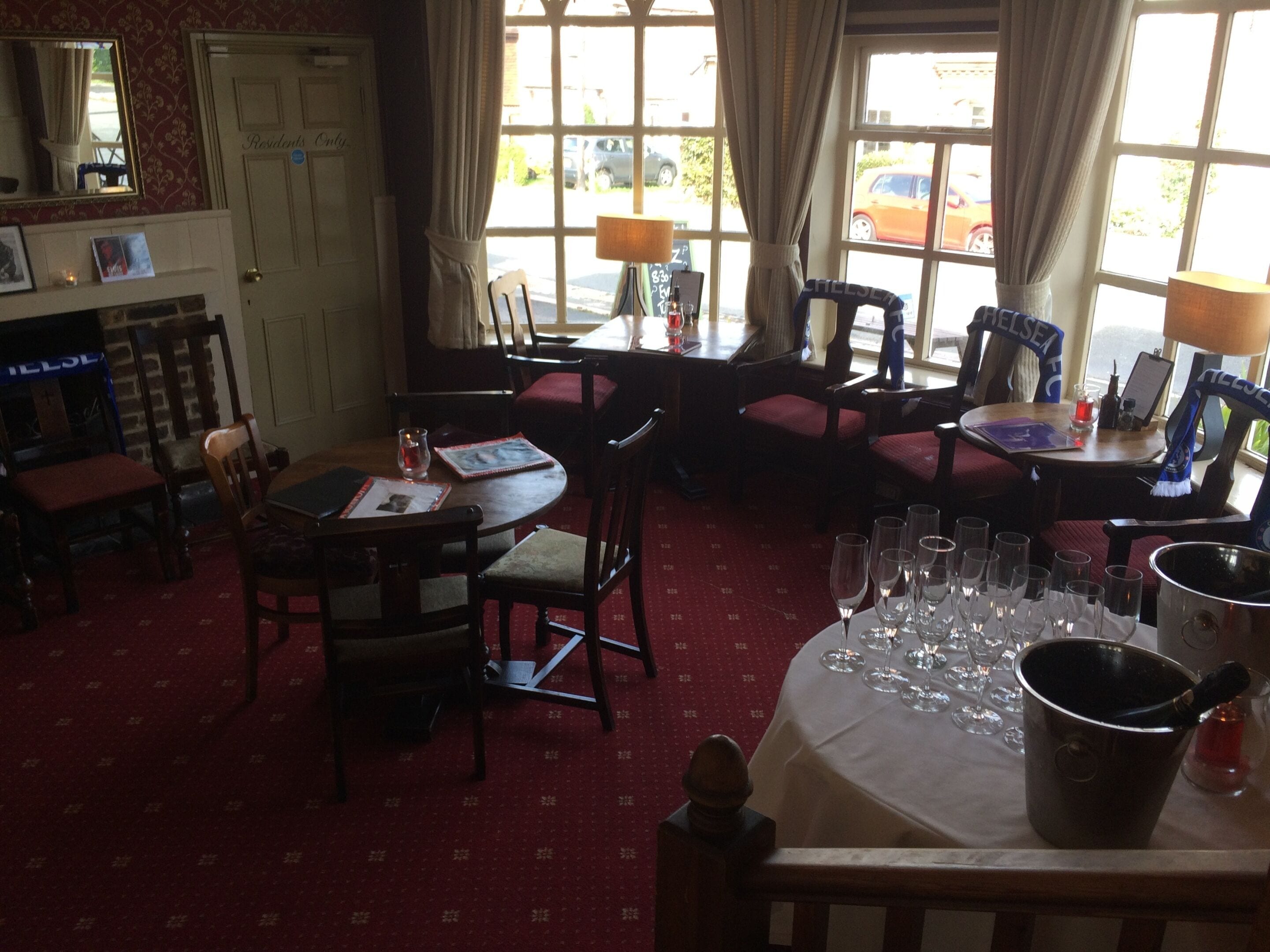 Un comedor con una mesa dispuesta para seis personas, sillas y un amplio ventanal con cortinas.