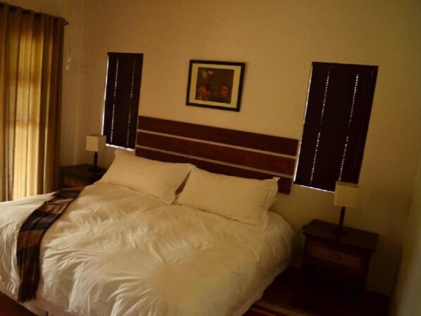 A neatly made bed with a wooden headboard, two bedside tables with lamps, and a framed picture on the wall.
