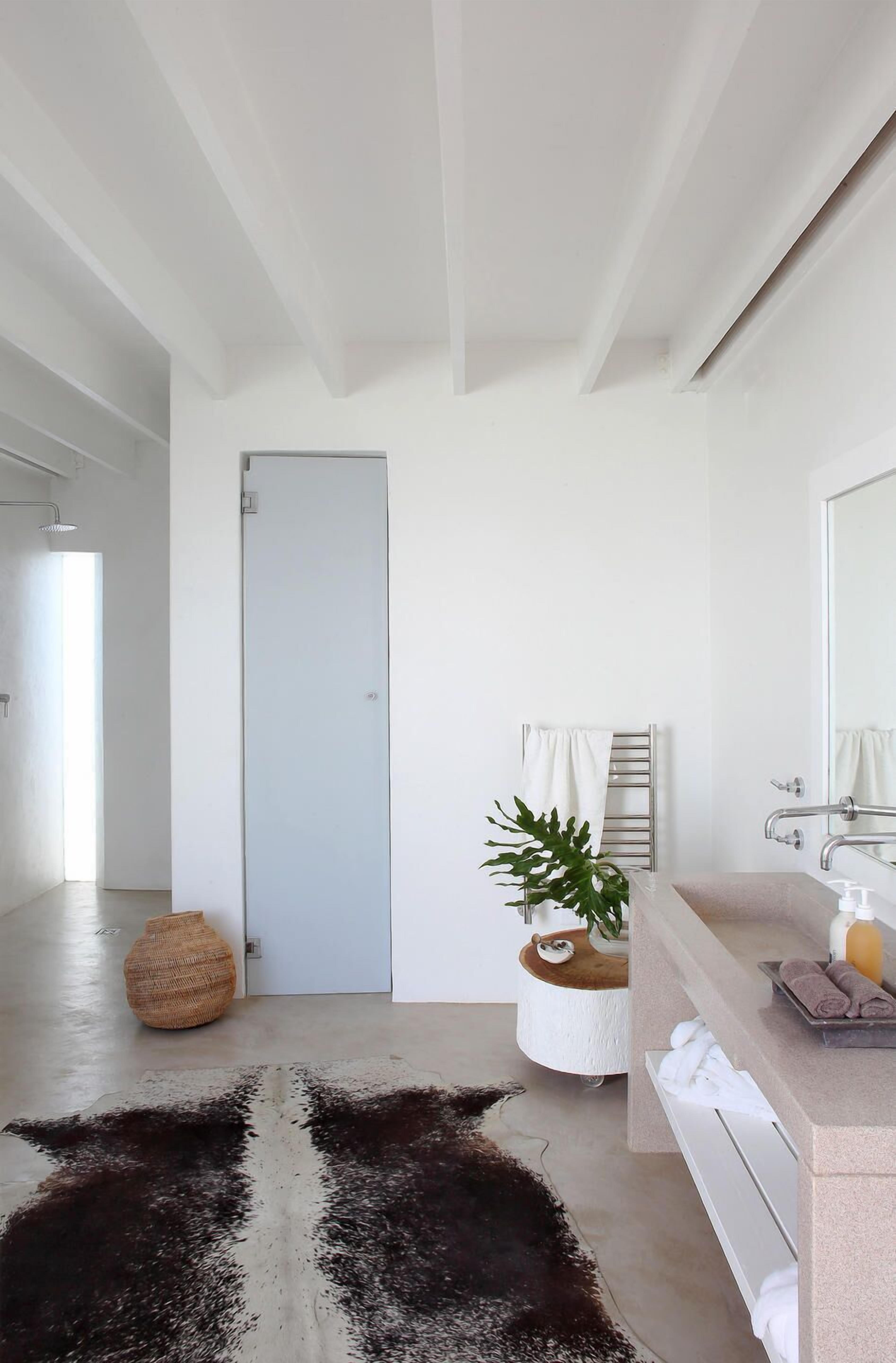 Un baño moderno con un lavamanos blanco, un espejo y un perchero para toallas.