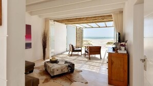 A room with a view of the beach, a wooden desk, a chair, and a sofa.