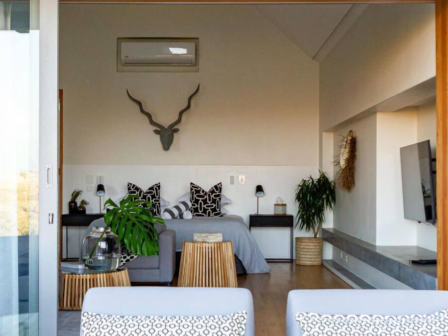 A modern bedroom with a large bed, a sofa, and a TV.