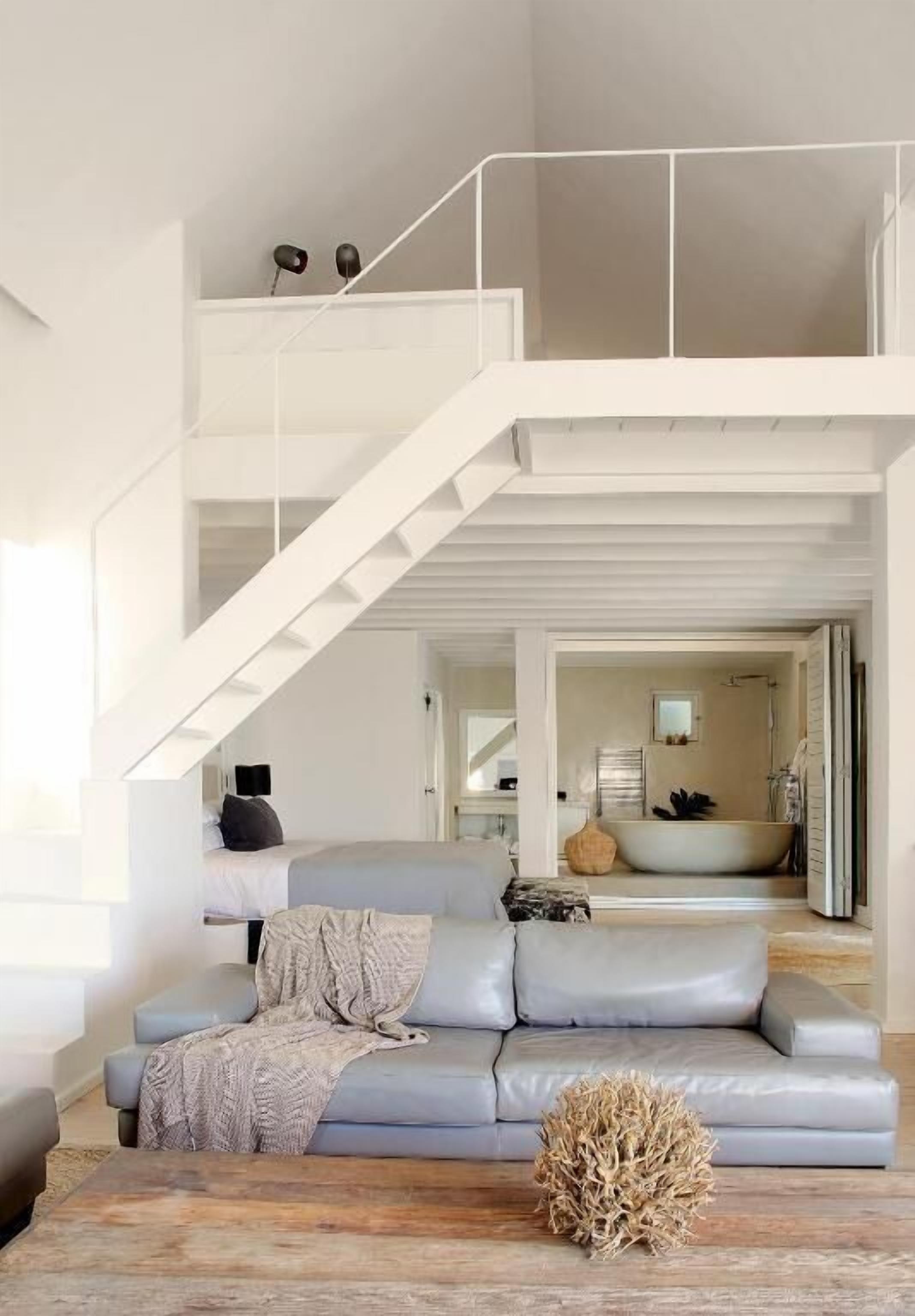 Un salon moderne avec un canapé gris, une table basse et un escalier menant à un niveau supérieur.