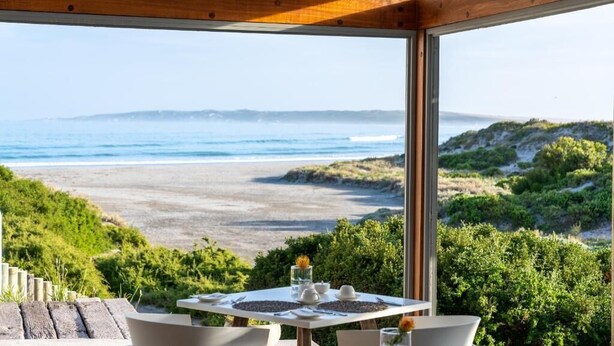 A table set for two with a view of the beach and ocean.