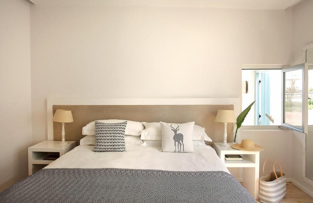 Un dormitorio ordenado con una cama grande, dos mesitas de noche y un ventanal con vistas.