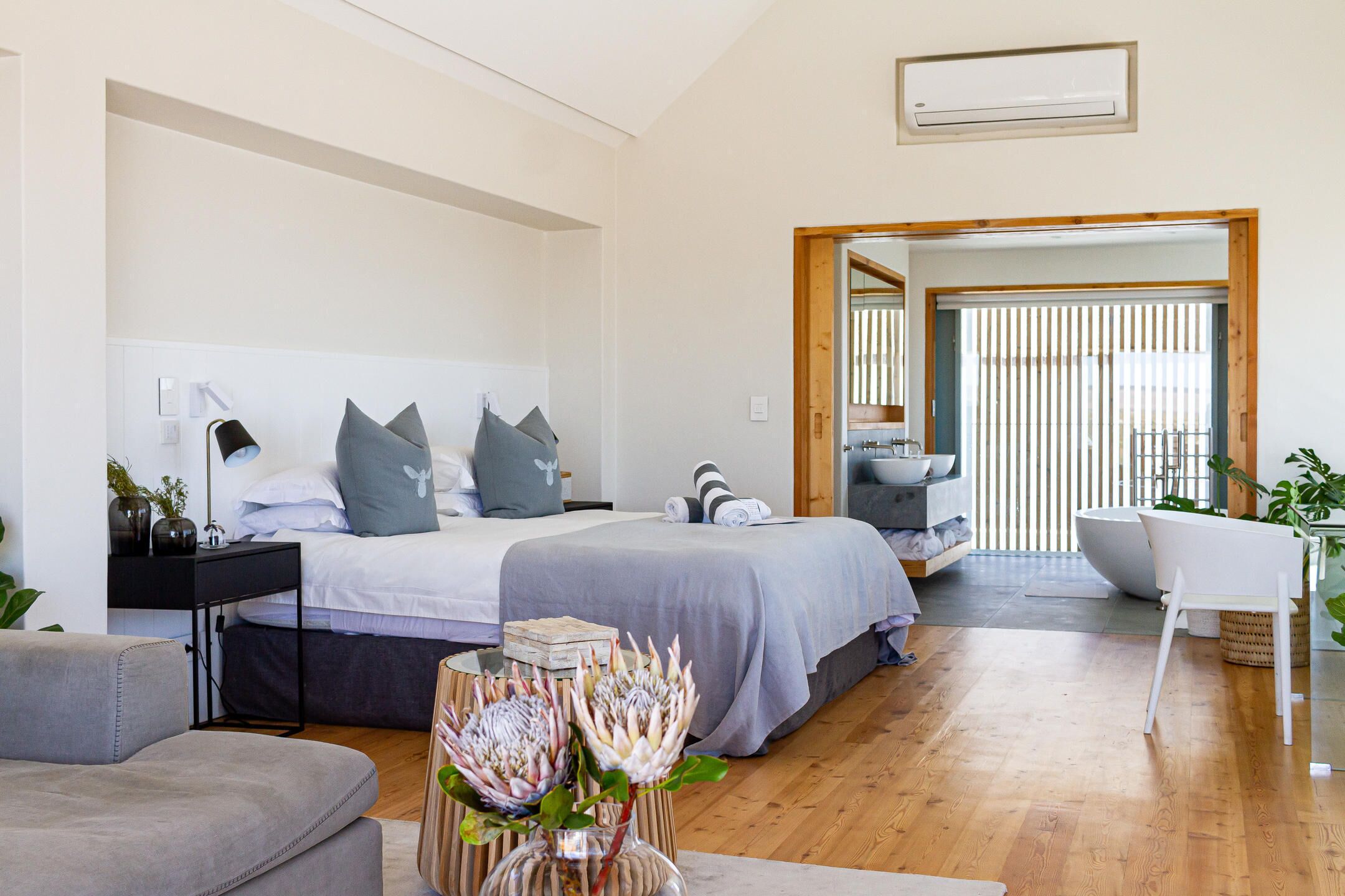 A modern bedroom with a large bed, bedside tables, a desk, and a chair.