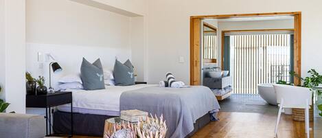 A modern bedroom with a large bed, bedside tables, a desk, and a chair.
