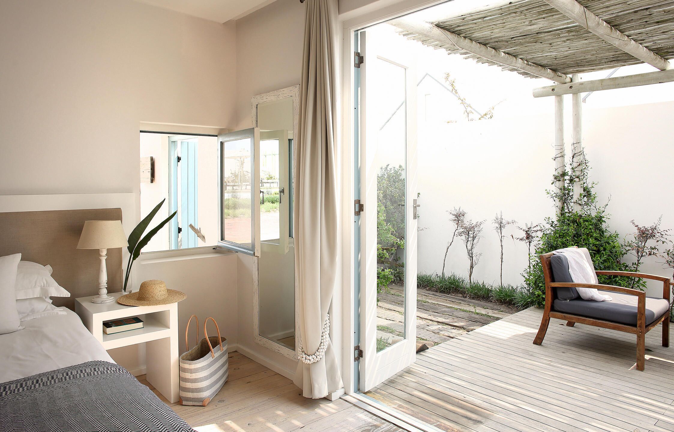 A bedroom with a bed, bedside table, lamp, and a view of the garden through a sliding door.