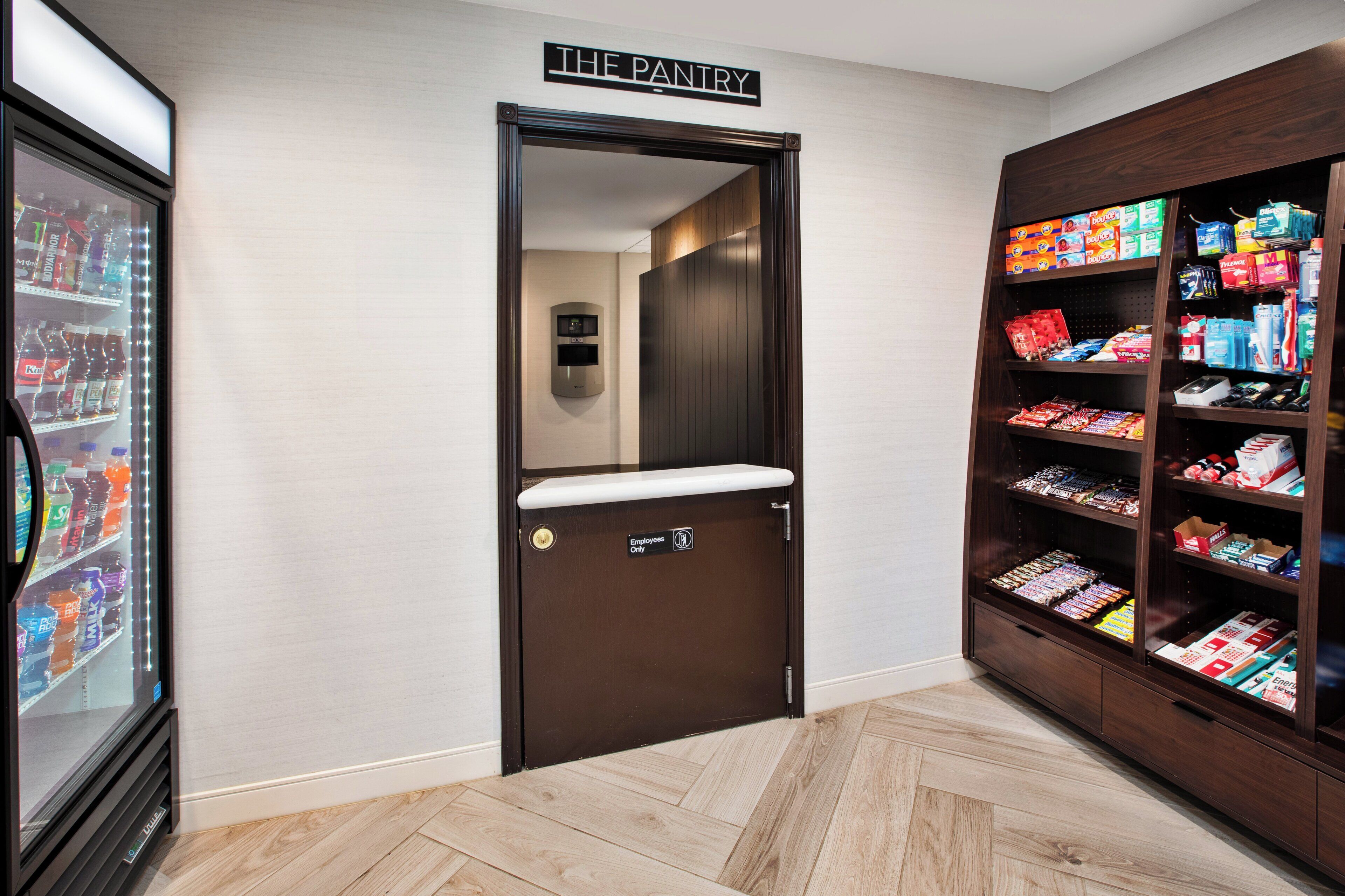 A pantry with shelves stocked with snacks and beverages, a refrigerator, and a door labeled "The Pantry."