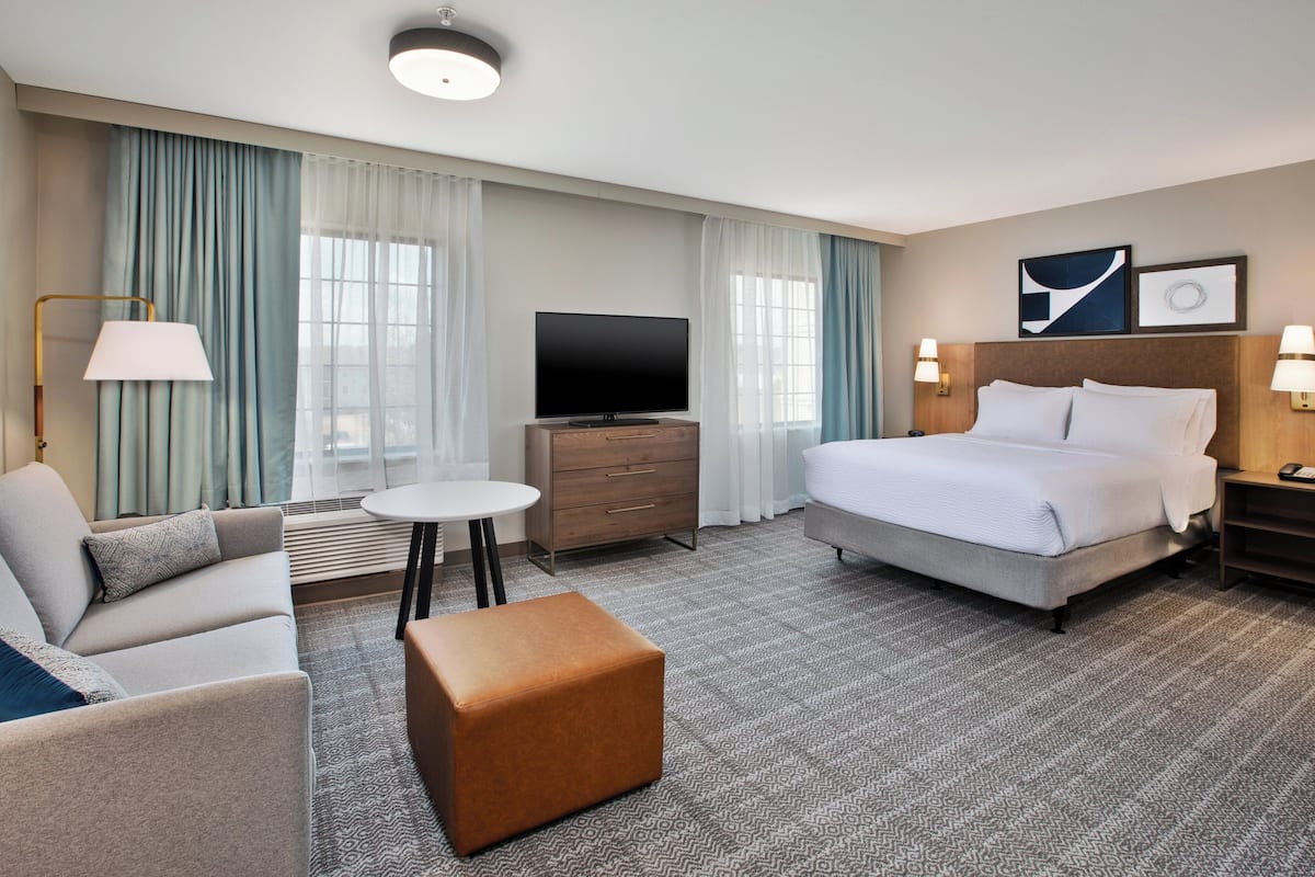 Ein Hotelzimmer mit Bett, Sofa, Fernseher, kleinem Tisch und Lampe.