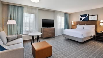 Una habitación de hotel con cama, sofá, televisión, una mesita y una lámpara.