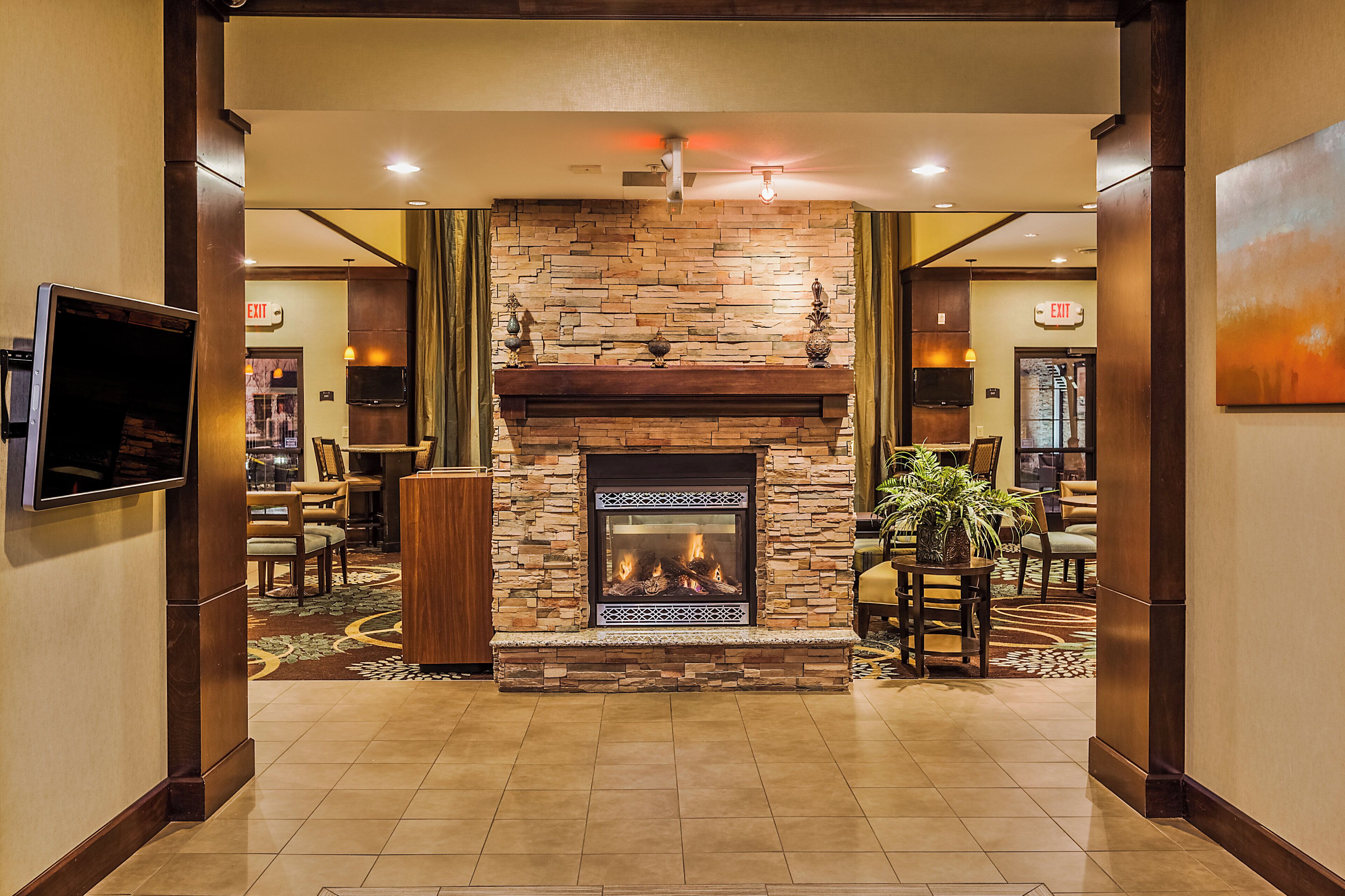 A lobby with a stone fireplace, seating area, and a television mounted on the wall.