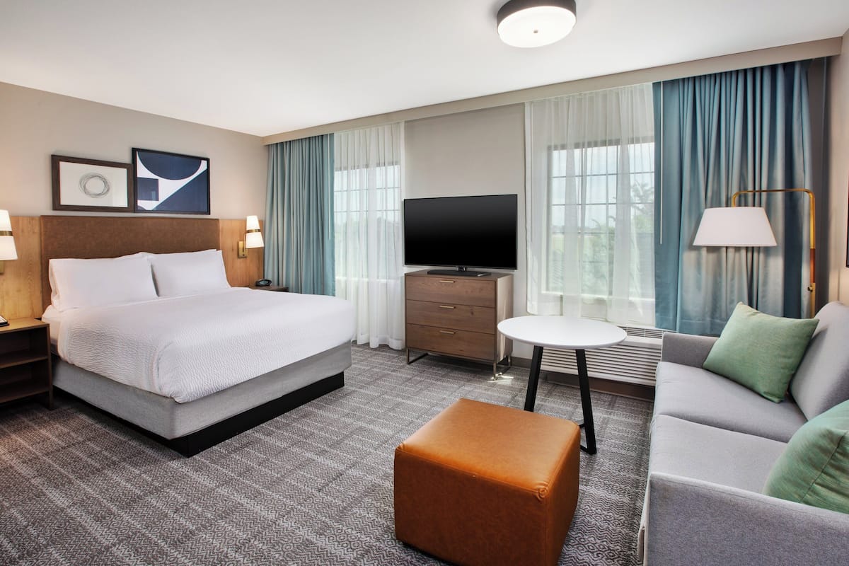 Ein Hotelzimmer mit Bett, Fernseher, Sofa, kleinem Tisch und Lampe.